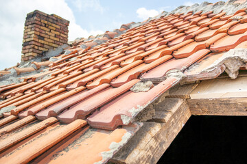 Time to repair the roof concept. Very old pyramid-shaped Decrepit roof with rotten lags. Red clay ceramic tiles