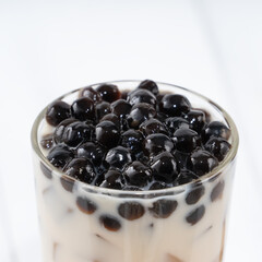 Bubble milk tea with tapioca pearl topping, famous Taiwanese drink on white wooden table background in drinking glass, close up, copy space