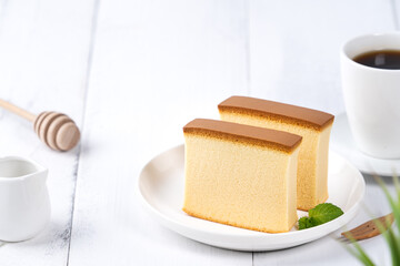 Castella (kasutera) - Beautiful delicious Japanese sliced sponge cake food on white plate over rustic white wooden table, close up, copy space design concept.