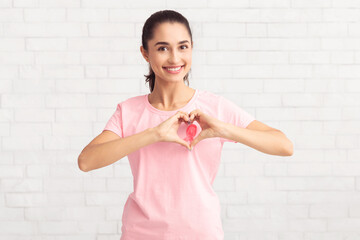 Woman Gesturing Heart Shape Framing Ribbon On T-Shirt, White Background