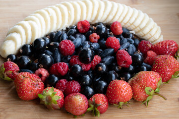 background of currant, raspberry, honeysuckle, Victoria and sliced banana on the cutting Board
