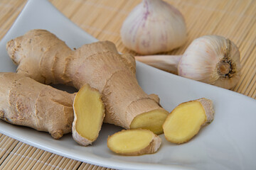 Ingwer, Ingwerwurzel in einer weissen Schale und frischem Knoblauch