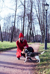 pretty young girl in redd coat playing with dog outside in green park, lifestyle people concept