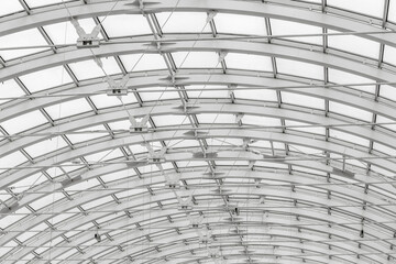 The transparent roof of a large shopping center in the form of an arch with lamps. Black and white photographs of buildings.