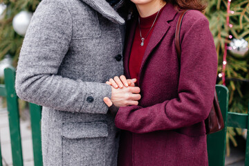 Young couple holding hands outdoors in a coat