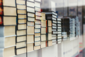 Many identical books are stacked on top of each other in a glass display case of a bookstore.