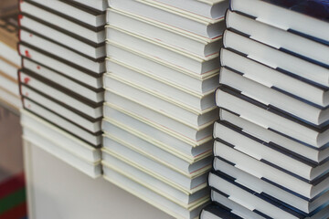 Many identical books are stacked on top of each other in a glass display case of a bookstore.