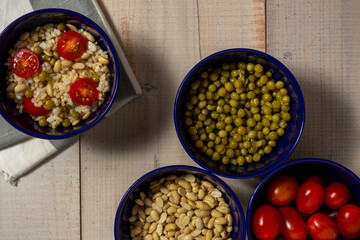 Obraz na płótnie Canvas Arroz integral con tomate, porotos de soja y arvejas en varios recipientes, concepto de comida saludable y vegana, vista desde arriba