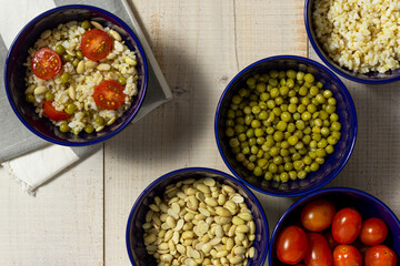 Arroz integral con tomate, porotos de soja y arvejas en varios recipientes, concepto de comida saludable y vegana, vista desde arriba
