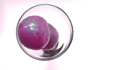  two plums in a glass cup on a white background      