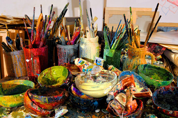 Paint brushes and containers on the artist's table.