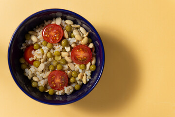 Arroz integral con tomate, porotos de soja y arvejas en un recipiente, concepto de comida saludable y vegana, vista desde arriba