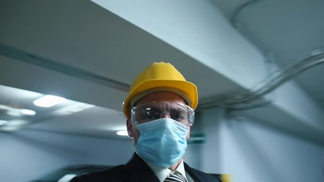 A man in a mask and a helmet on his head spins in place. Worker dizzy at work. Symptoms of the disease at work. Online call. Communication over a long distance.