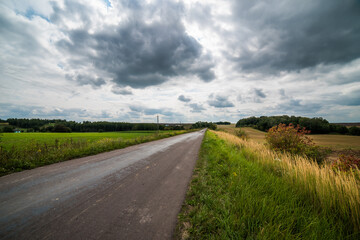 Fototapeta na wymiar Road in a field under thunder clouds.