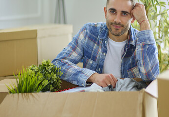 A moving man sitting on the floor in empty apartment, Among the Boxes, Checking the List of Things