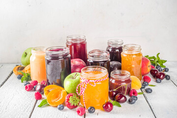 Assortment of berries and fruits jams. Set of various seasonal summer berry and fruit jam, marmalade and confitures. White wooden background copy space