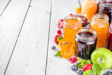 Assortment of berries and fruits jams. Set of various seasonal summer berry and fruit jam, marmalade and confitures. White wooden background copy space