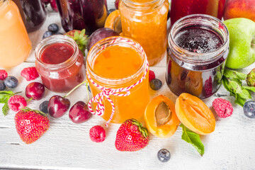 Assortment of berries and fruits jams. Set of various seasonal summer berry and fruit jam, marmalade and confitures. White wooden background copy space