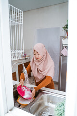 muslim woman doing chores and washing the dishes