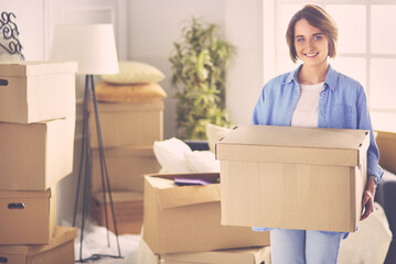 Portrait of pretty woman holding a box at new home