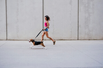 happy young woman walking outdoors with beagle dog. Family and lifestyle concept