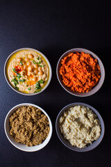 Plates with tasteful vegetable sauces, overhead on black background