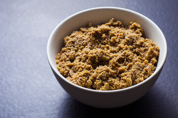Ground olive spread in bowl on dark grey surface