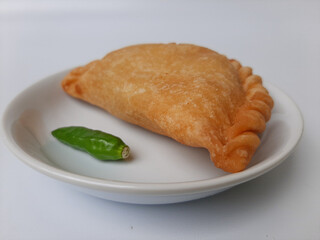 Pastel, is a pastry filled with chicken meat and mixed vegetable, then deep fried. Snack from Indonesia. On white plate. Isolated in white background.