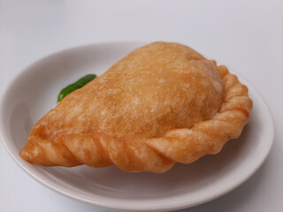 Pastel, is a pastry filled with chicken meat and mixed vegetable, then deep fried. Snack from Indonesia. On white plate. Isolated in white background.