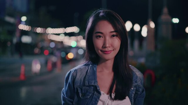 A woman smiling in the city at night.