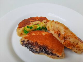 Pukis, is an Indonesian traditional pancake, with various toppings. On white plate. Isolated in white background.