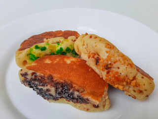 Pukis, is an Indonesian traditional pancake, with various toppings. On white plate. Isolated in white background.