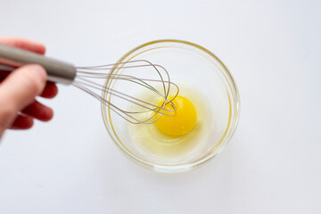 Woman Whipping eggs in glass bowl with whisk