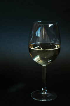 Glass of white wine on a black background. Vertical photo