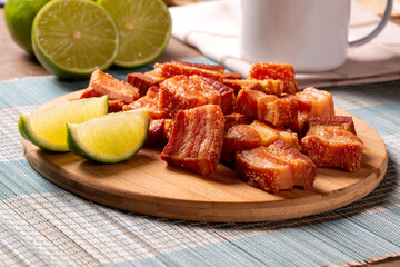 Deep fried crispy pork belly served with two half lemon on the table.