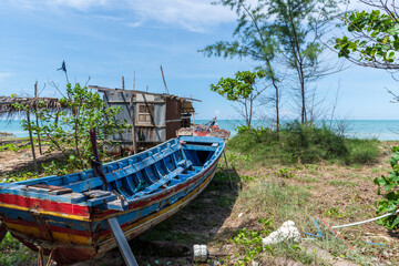 Naklejka na ściany i meble A old and broken wooden fishing boat on the beach in the coastal grass