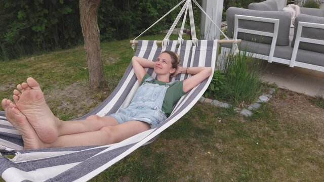 Slow motion shot of smiling woman relaxing in hammock