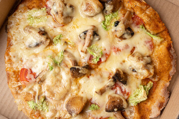 Vegetarian pizza with mushrooms near the ingredients in a cardboard box close-up, top view