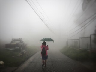 Woman with umbrella on a foggy road in Baguio City.