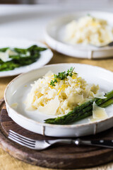 Creamy lemon risotto with parmesan and asparagus on white plate.