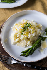 Creamy lemon risotto with parmesan and asparagus on white plate.