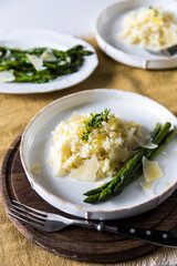 Creamy lemon risotto with parmesan and asparagus on white plate.