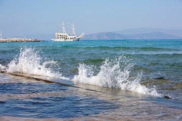 water splashes in the sea. in the distance a cruise ship sails into the sea.