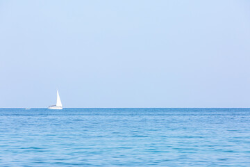 lonely white sail in front of cloudless sky.