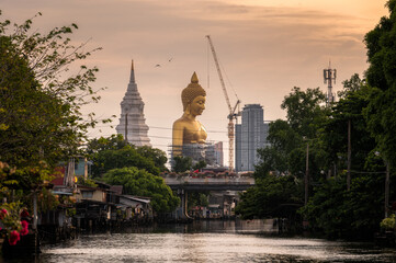 Large golden buddha with pagoda in traditional community on riverside at Bangkok