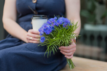 a bouquet of cornflowers in the womens hand close-up.