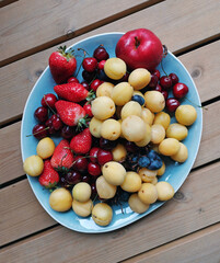 fruit plate with berries on a knitted blanket. Apricots strawberries cherries and an apple.