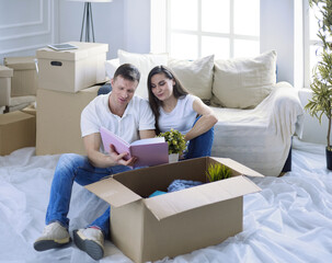 Cute couple unpacking cardboard boxes in their new home