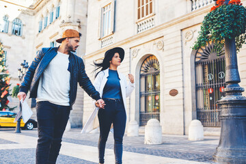Handsome man with a beard leads his stylish girl by the hand through the city. Serious young people...