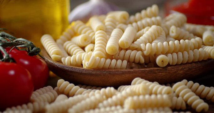 Dry pasta fusilli with tomatoes and oil slowly rotates.